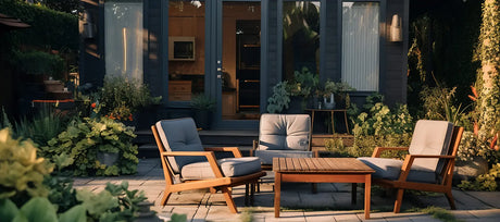 Loungebereich mit Holzsesseln und Couchtisch auf Terrasse vor Gartenhaus in Abendstimmung