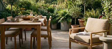 Terrasse mit gedecktem Esstisch und Loungesessel zwischen Olivenbäumen und Farnen