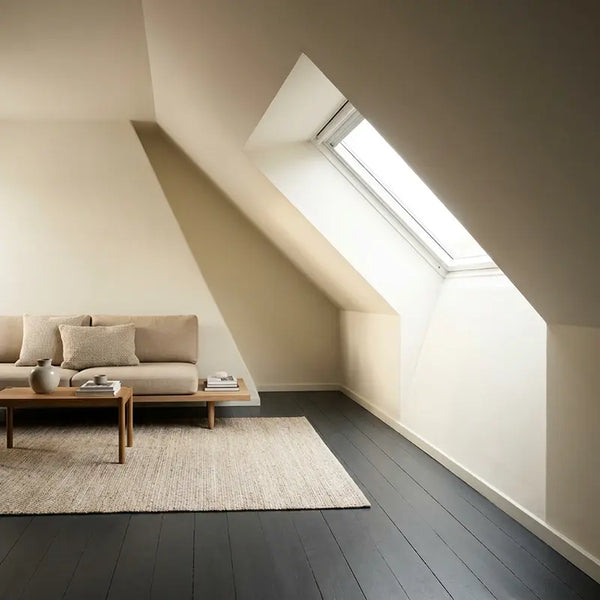 Wohnzimmer mit Dachschräge, hellen Wänden und dunklem Holzboden als bewusster Kontrast