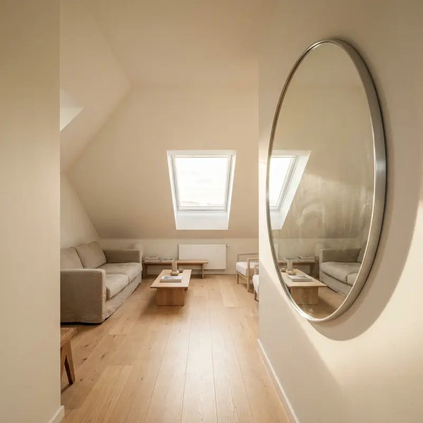 Runder Wandspiegel im Flur reflektiert Tageslicht und Sitzbereich im Dachschräge-Wohnzimmer