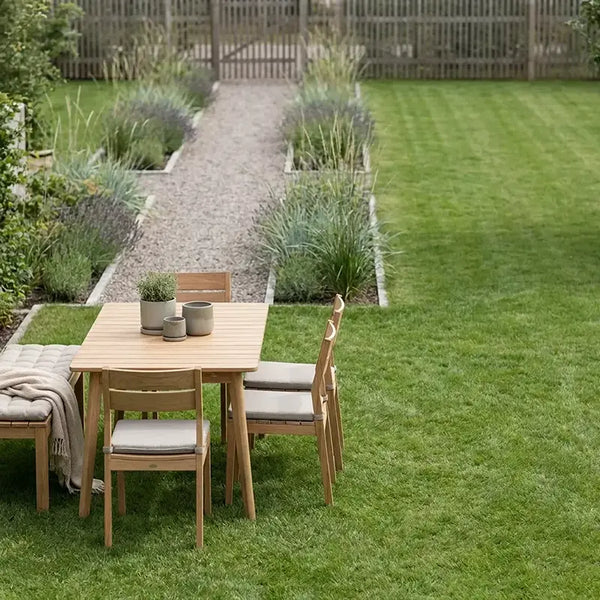 Holz-Essgruppe im Garten am Rasen neben Kiesweg mit Beeten