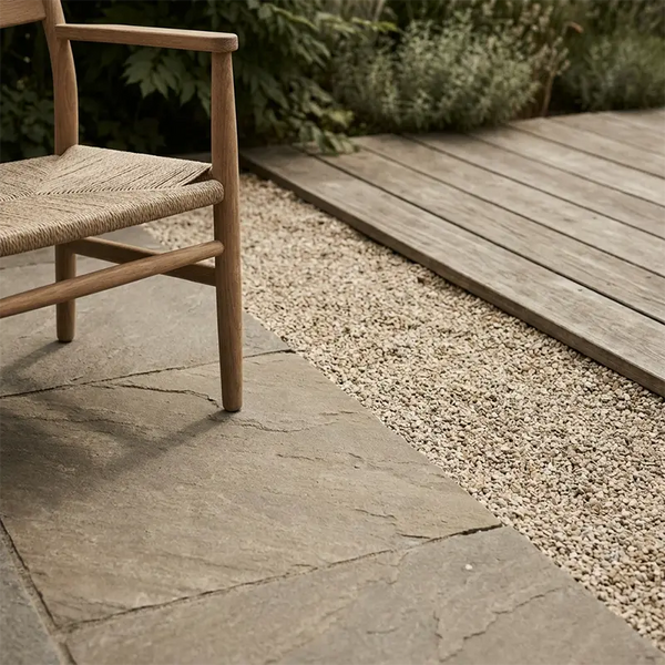Übergang von Natursteinplatten zu Kies und Holzterrasse im Garten