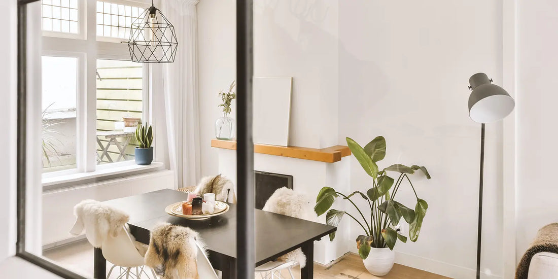 Kleines Esszimmer mit schwarzem Tisch und weißen Stühlen mit Fellauflagen unter geometrischer Draht-Pendelleuchte