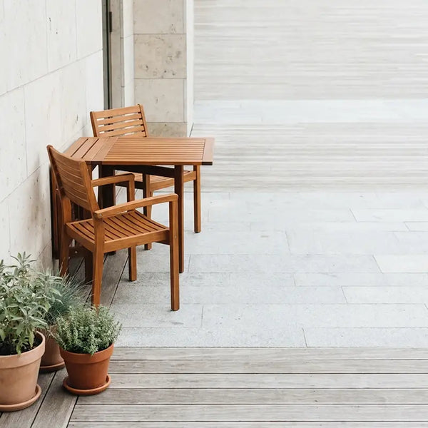 Kleiner Holztisch mit Stühlen platzsparend an Terrassenwand, Kräutertöpfe