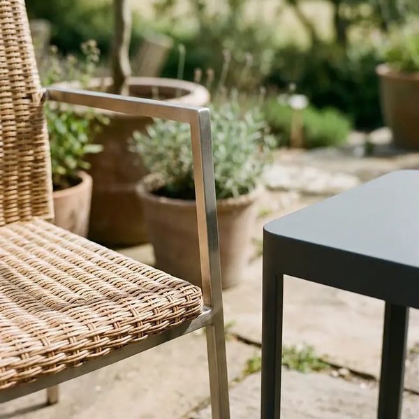 Detailaufnahme Rattanstuhl mit Metallarmlehne neben Metalltisch auf Terrasse